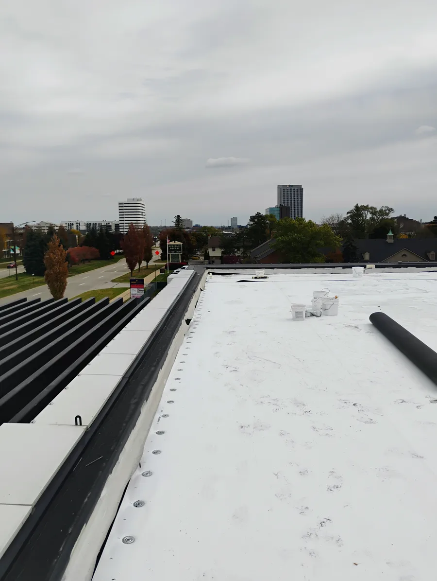 Metro Detroit flat roof crew on a large commercial roofing project with city skyline