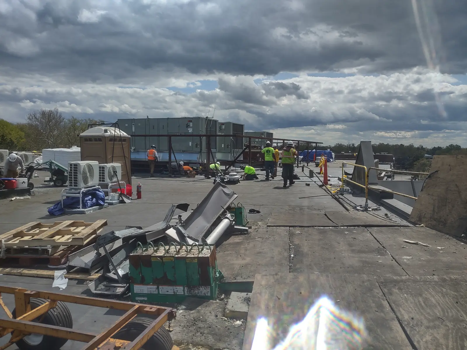 Commercial flat roof removal in progress with HVAC equipment and dramatic cloudy sky overhead, Metro Detroit