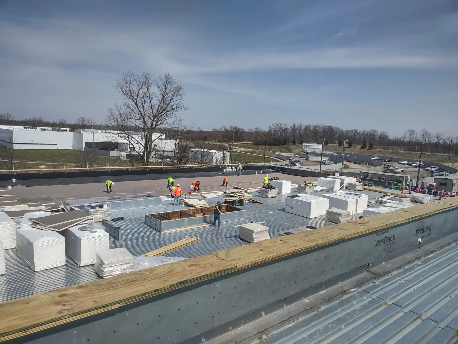 Wide view of large industrial commercial roof with crew staging insulation boards before EPDM installation, Metro Detroit
