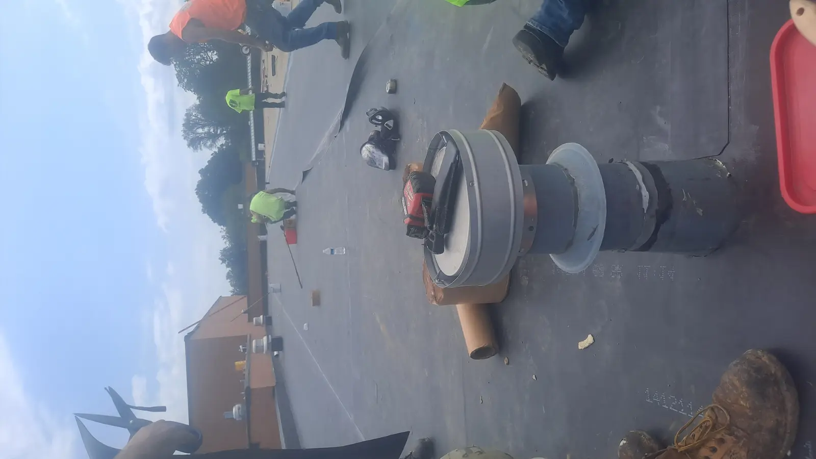 Roofers working around roof penetration boot on commercial EPDM flat roof installation, Metro Detroit