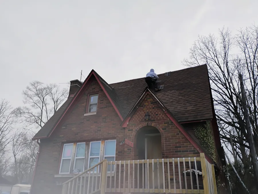 Technician on historic brick home performing roof repair in Metro Detroit