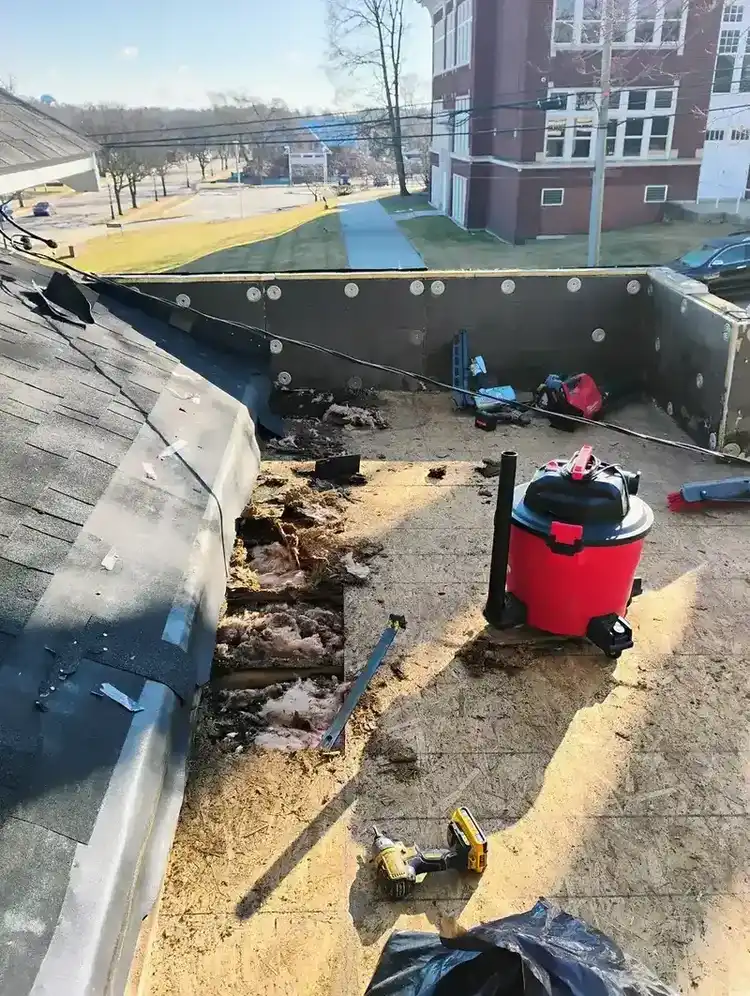 Full flat roof tear-off in progress exposing deck and damaged insulation before replacement