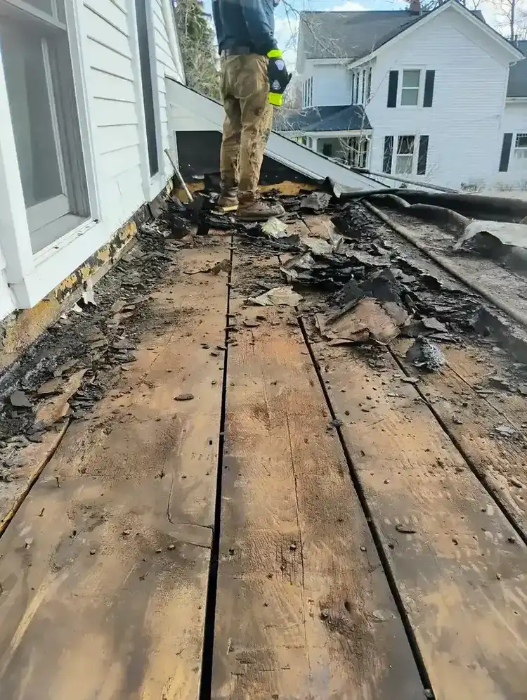 Full flat roof tear-off exposing old rotted wood plank deck before replacement, residential Metro Detroit