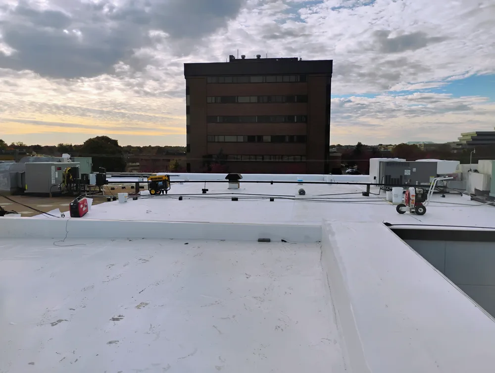Completed large-scale commercial TPO flat roof installation in Metro Detroit at sunset with HVAC equipment on white membrane